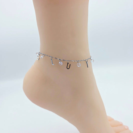 Ankle bracelet with letters on a foot against a light background