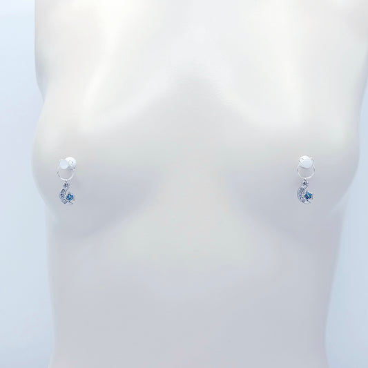 A pair of silver crescent moon and star dangle nipple rings with clear rhinestones and light blue star accents, shown on a plain light gray background.