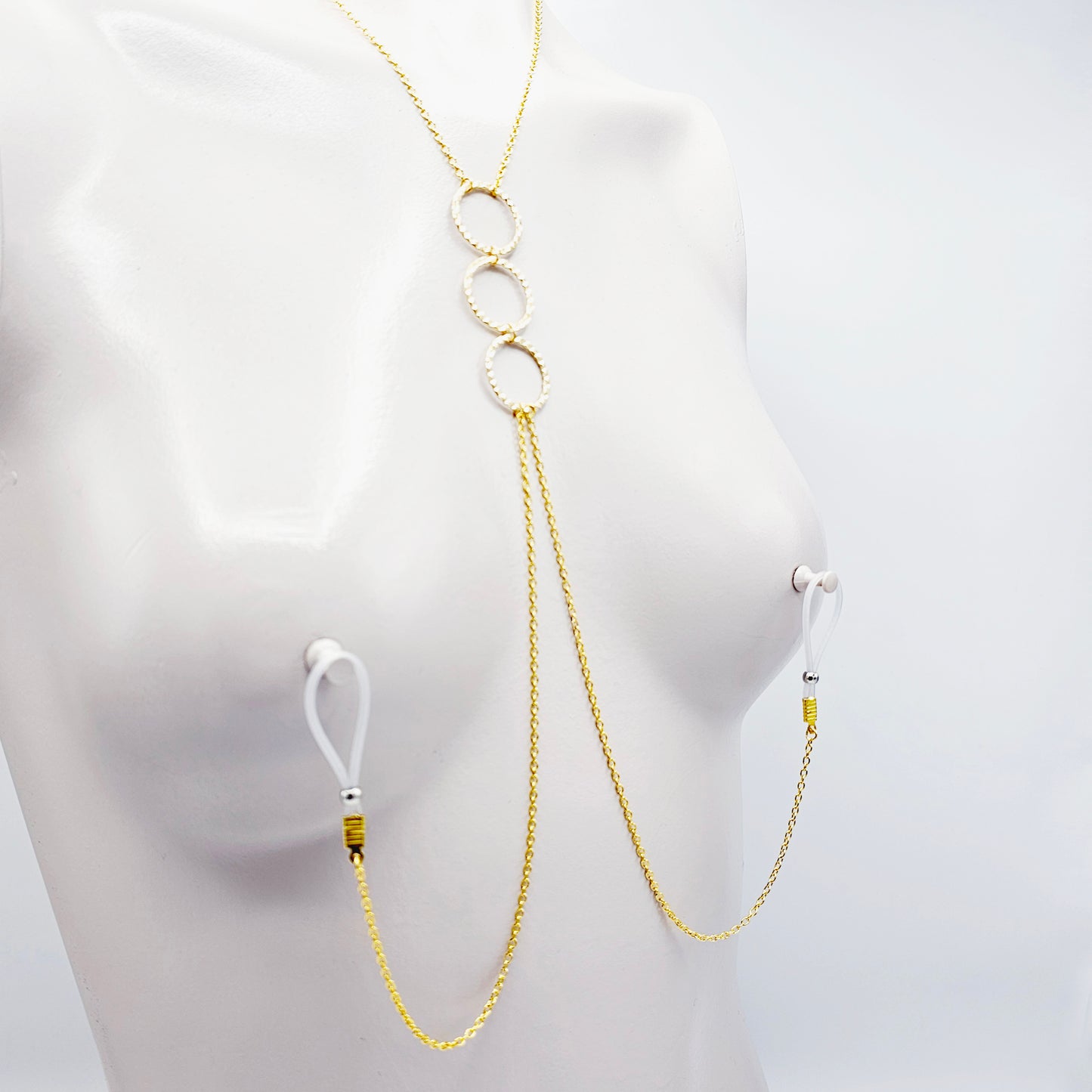 Gold Tri circle necklace attached to nipple nooses or feel the sting with one of our five types of nipple clamps.