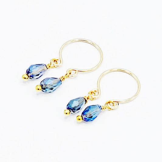 A pair of gold-colored non-piercing nipple rings with blue crystal dangles.