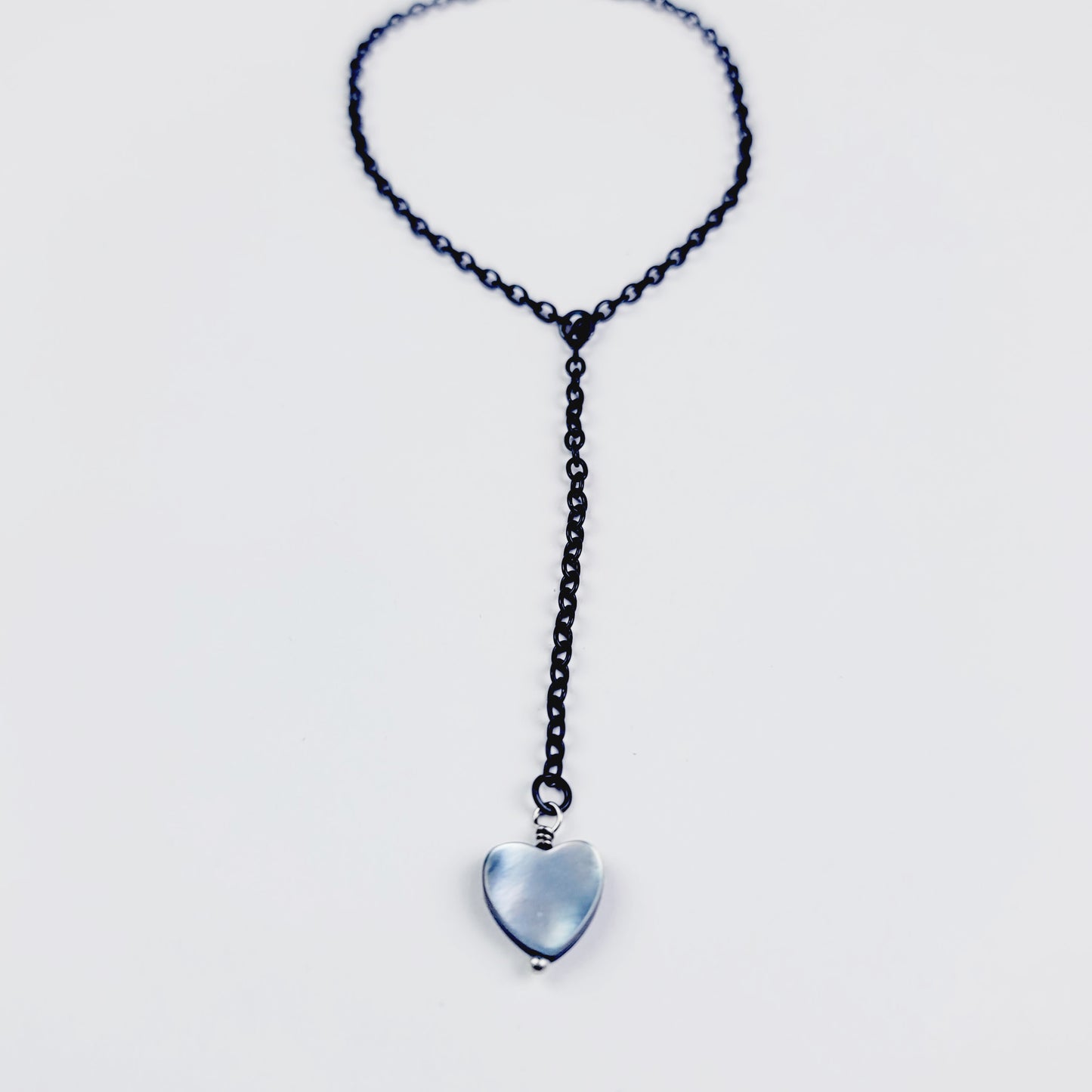 This image displays an adjustable penis chain noose paired with a shell-shaped heart, crafted in sleek black and silver colors. The chain is designed to be non-piercing, making it versatile and comfortable for wear.