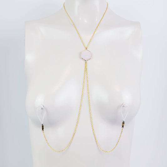 A mannequin showcasing a gold necklace with a semi-precious stone pendant, designed to extend to the nipple area, wearing non-piercing nipple nooses.