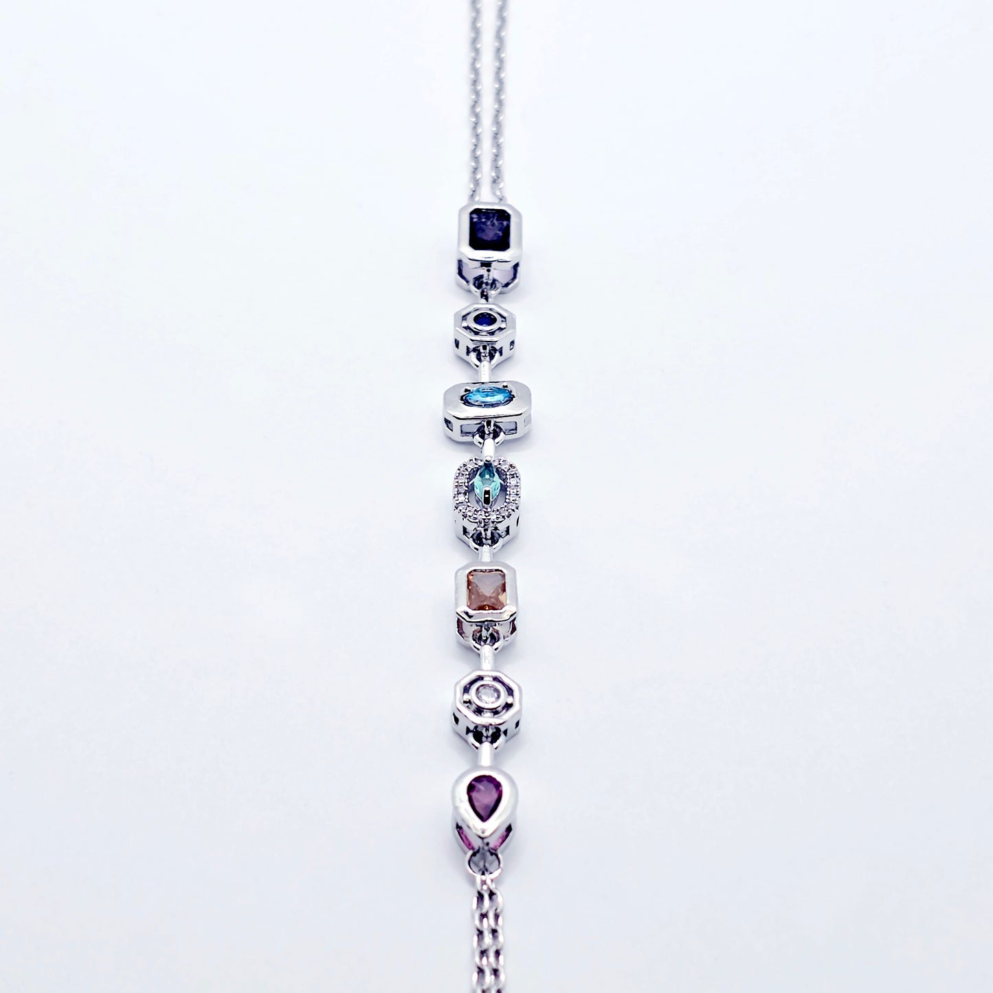 Platinum necklace with multicolored gemstones on a white background