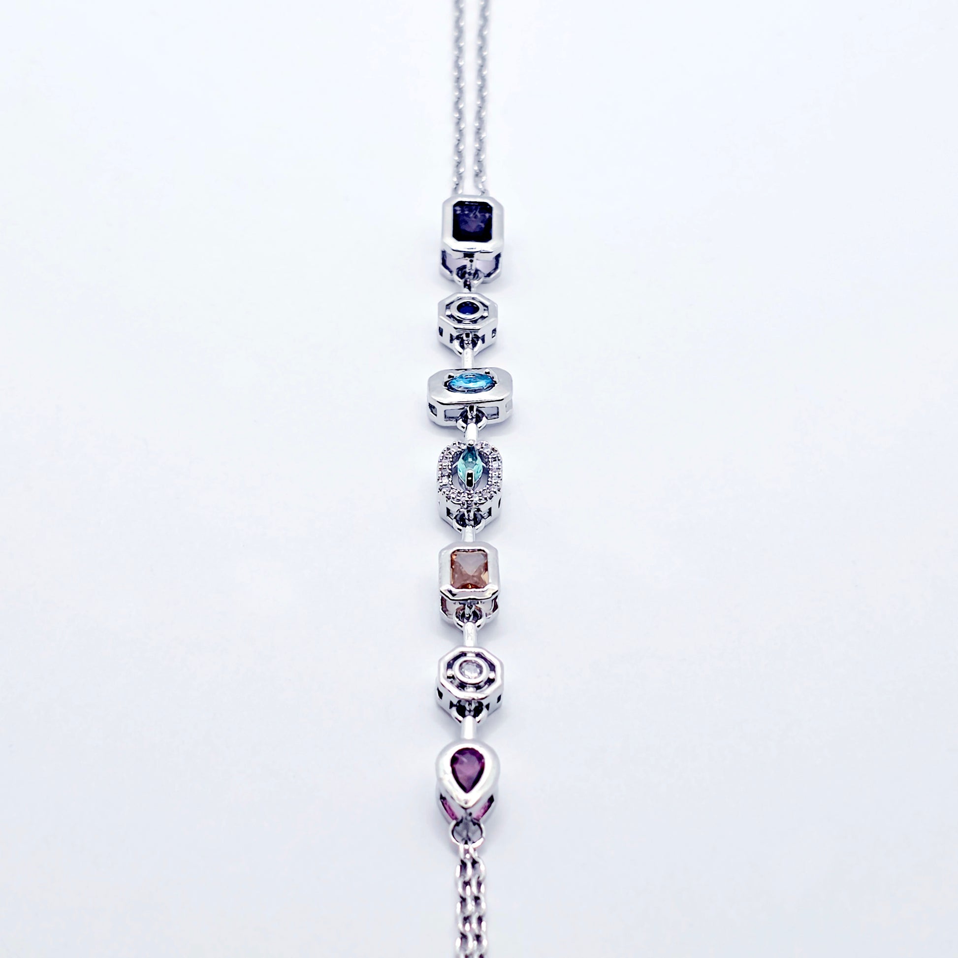 Platinum necklace with multicolored gemstones on a white background