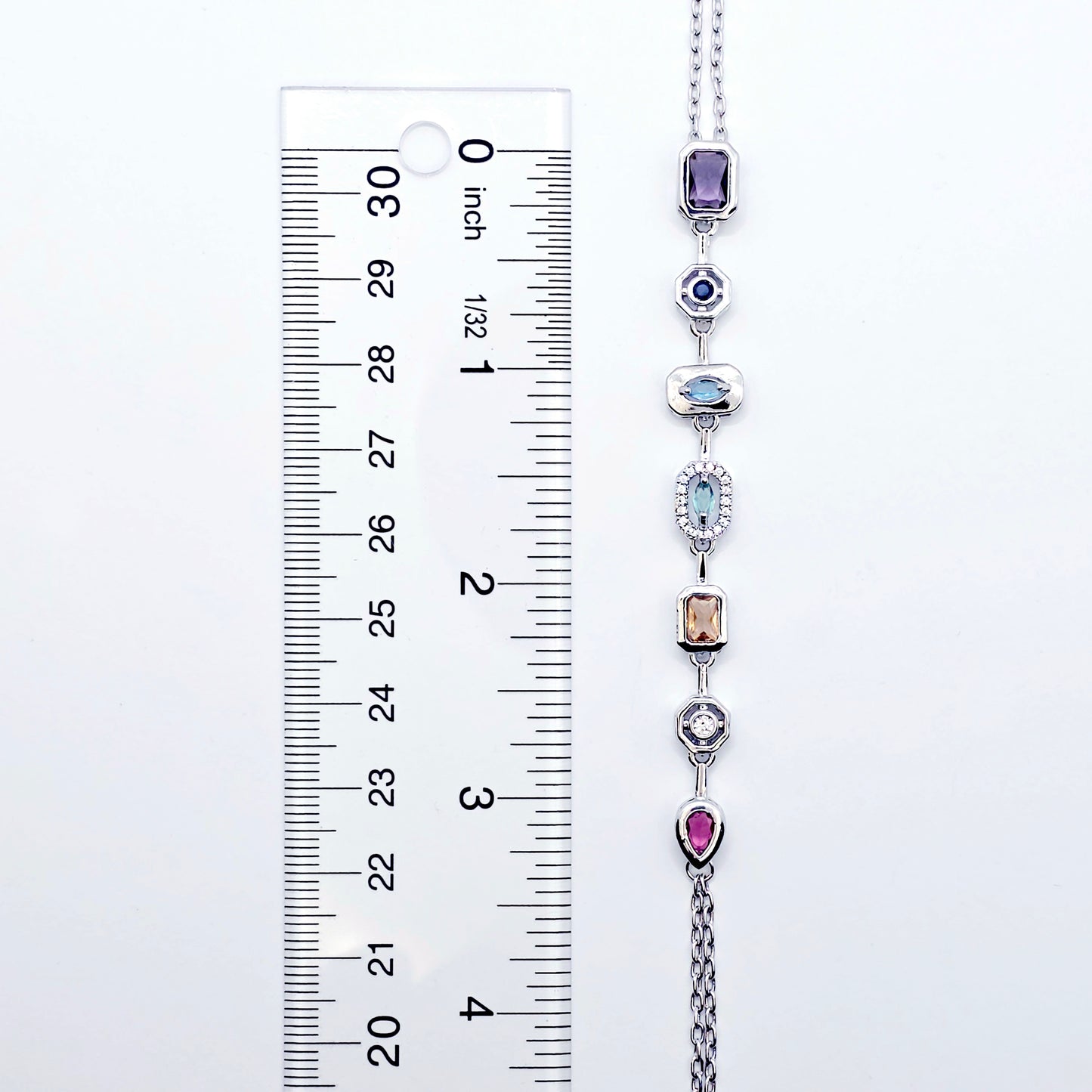 Necklace with colorful gemstones next to a ruler for size reference on a white background