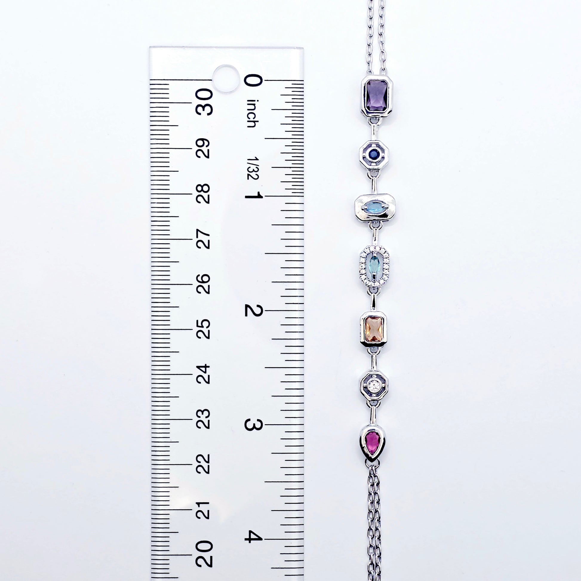 Necklace with colorful gemstones next to a ruler for size reference on a white background