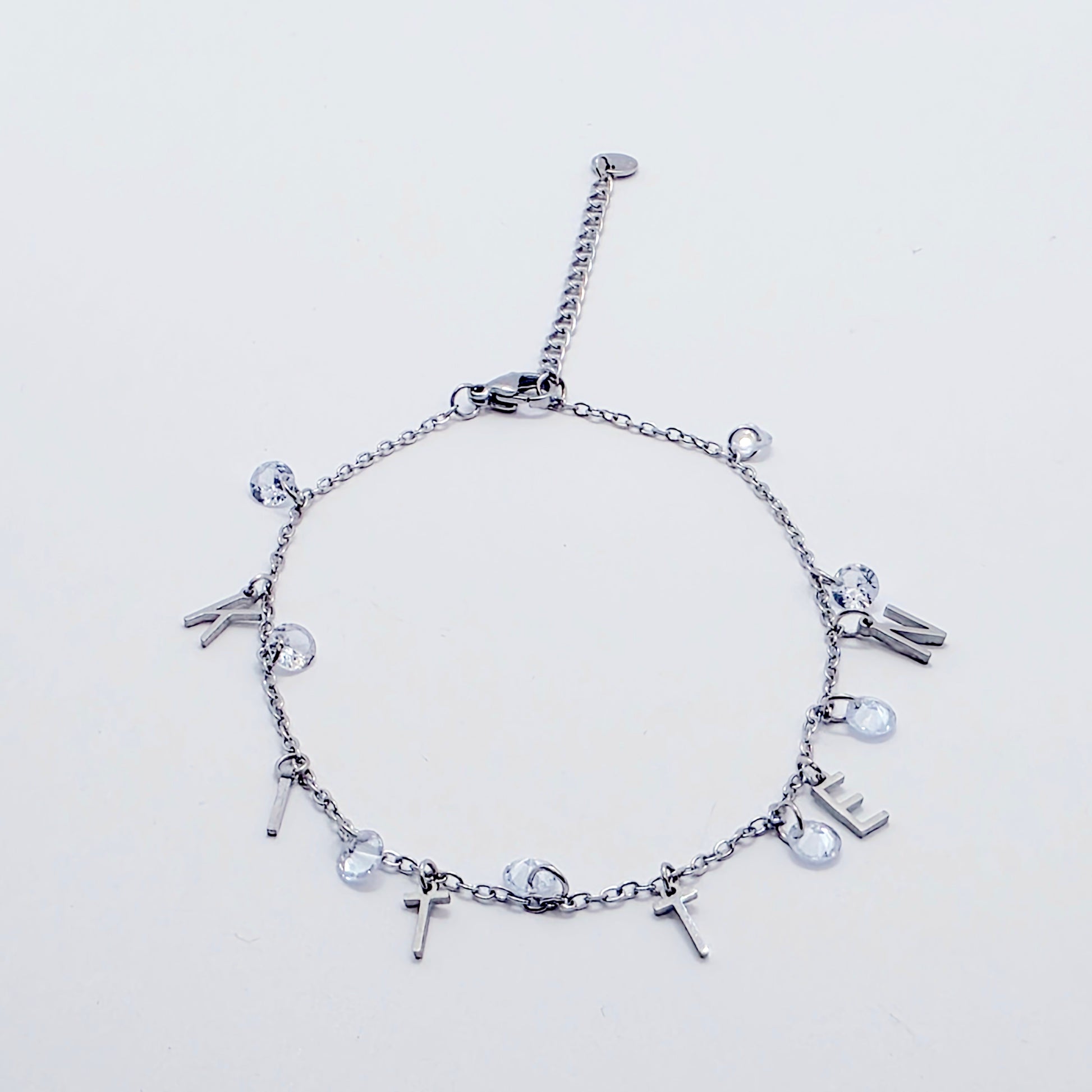 Silver bracelet with various charms on a light gray background