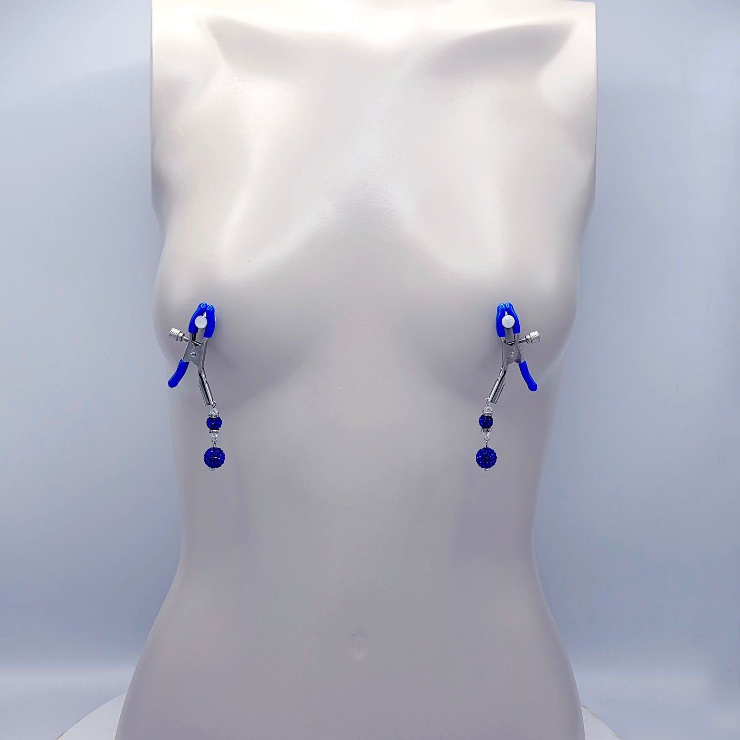 Blue and silver nipple clamps on a mannequin bust against a white background