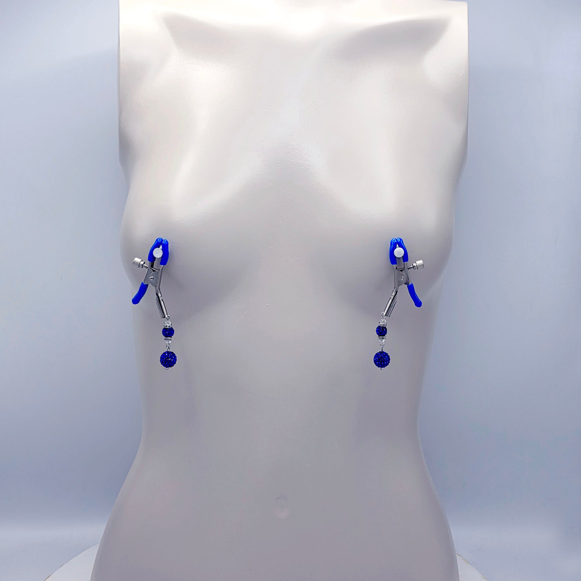 Blue and silver nipple clamps on a mannequin bust against a white background
