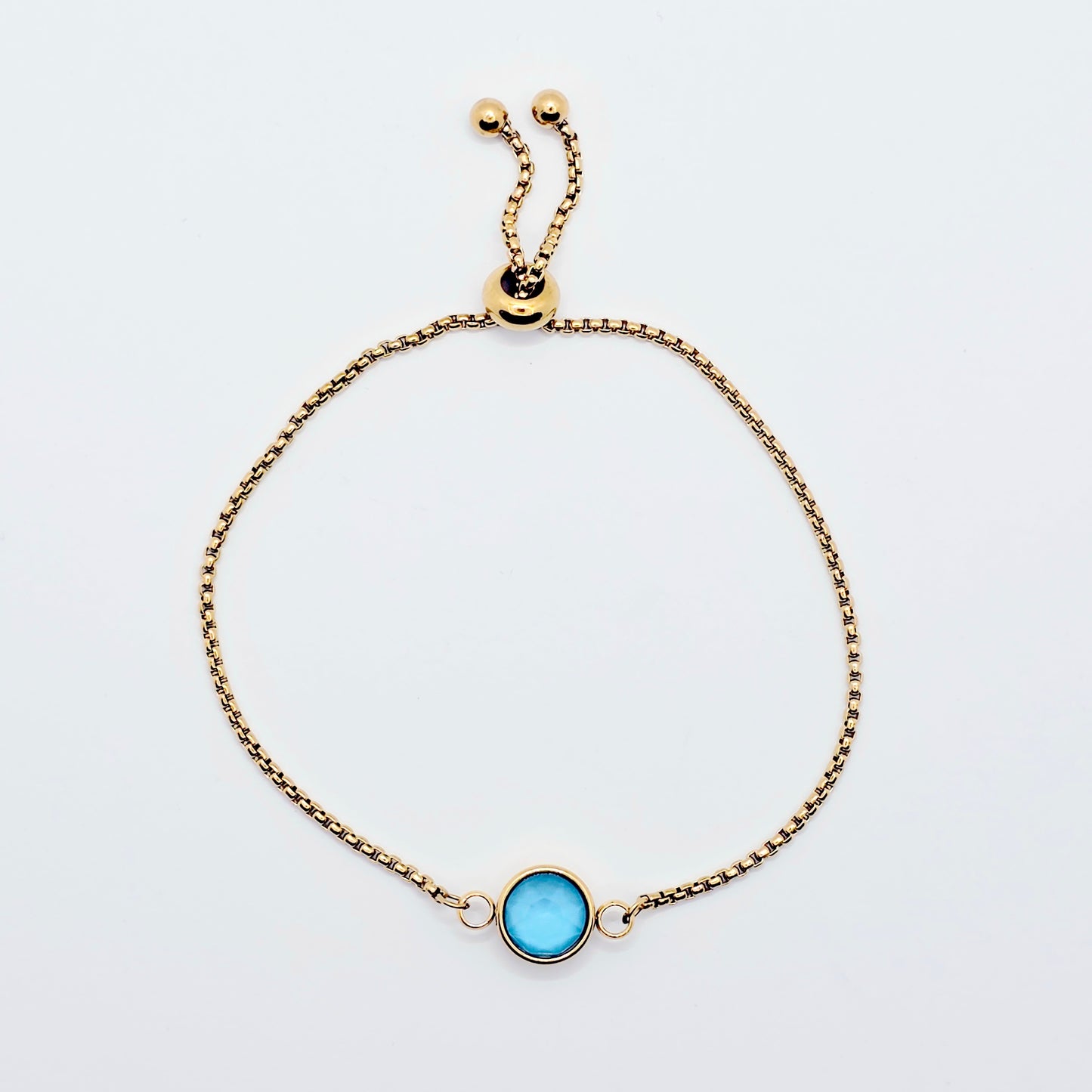 Gold penis noose bracelet with a blue gemstone on a light gray background