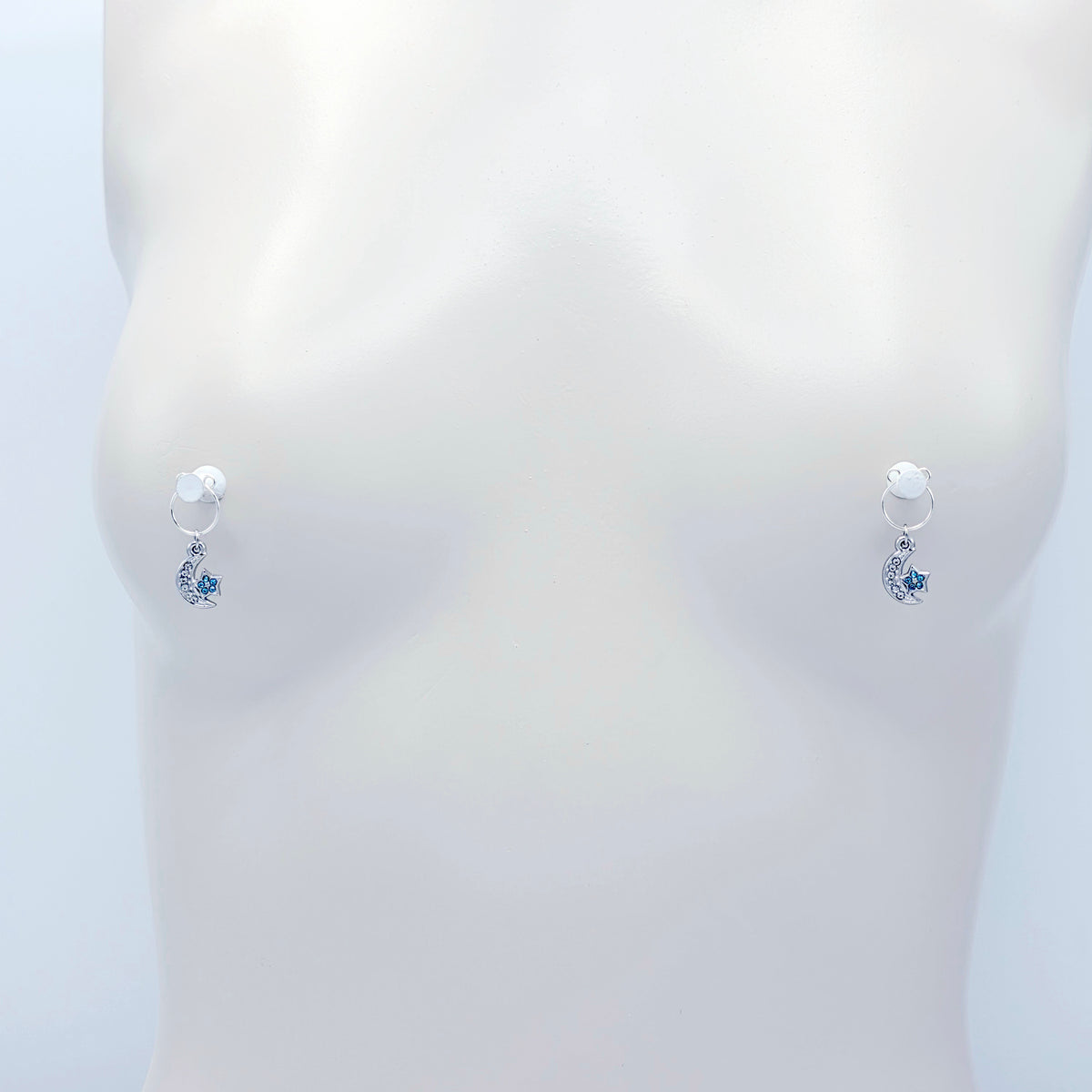 A pair of silver crescent moon and star dangle nipple rings with clear rhinestones and light blue star accents, shown on a plain light gray background.