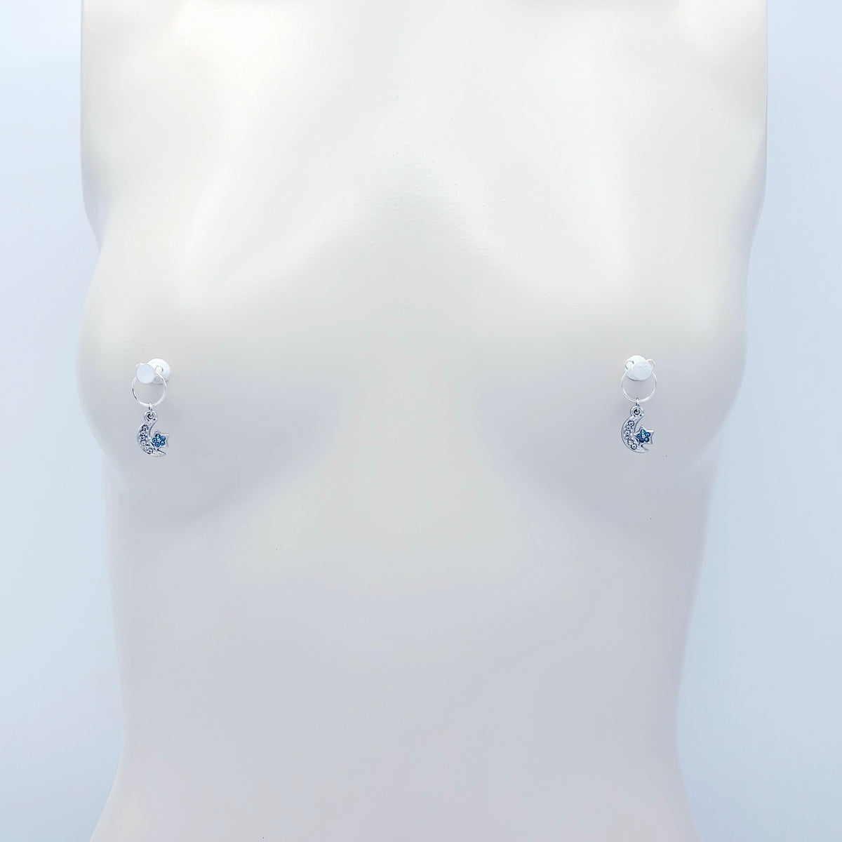 A pair of silver crescent moon and star dangle nipple rings with clear rhinestones and light blue star accents, shown on a plain light gray background.
