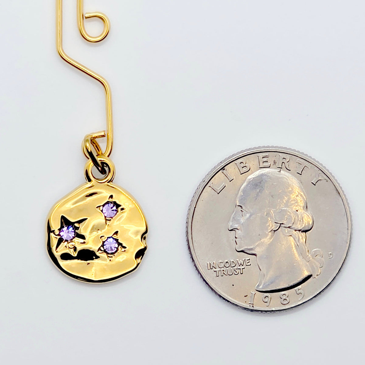 Gold Labia Clip with purple gem Stars next to quarter to show size