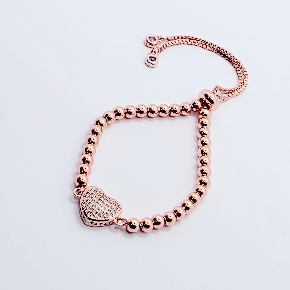 A rose gold beaded bracelet with a heart-shaped charm, displayed on a clean white background.