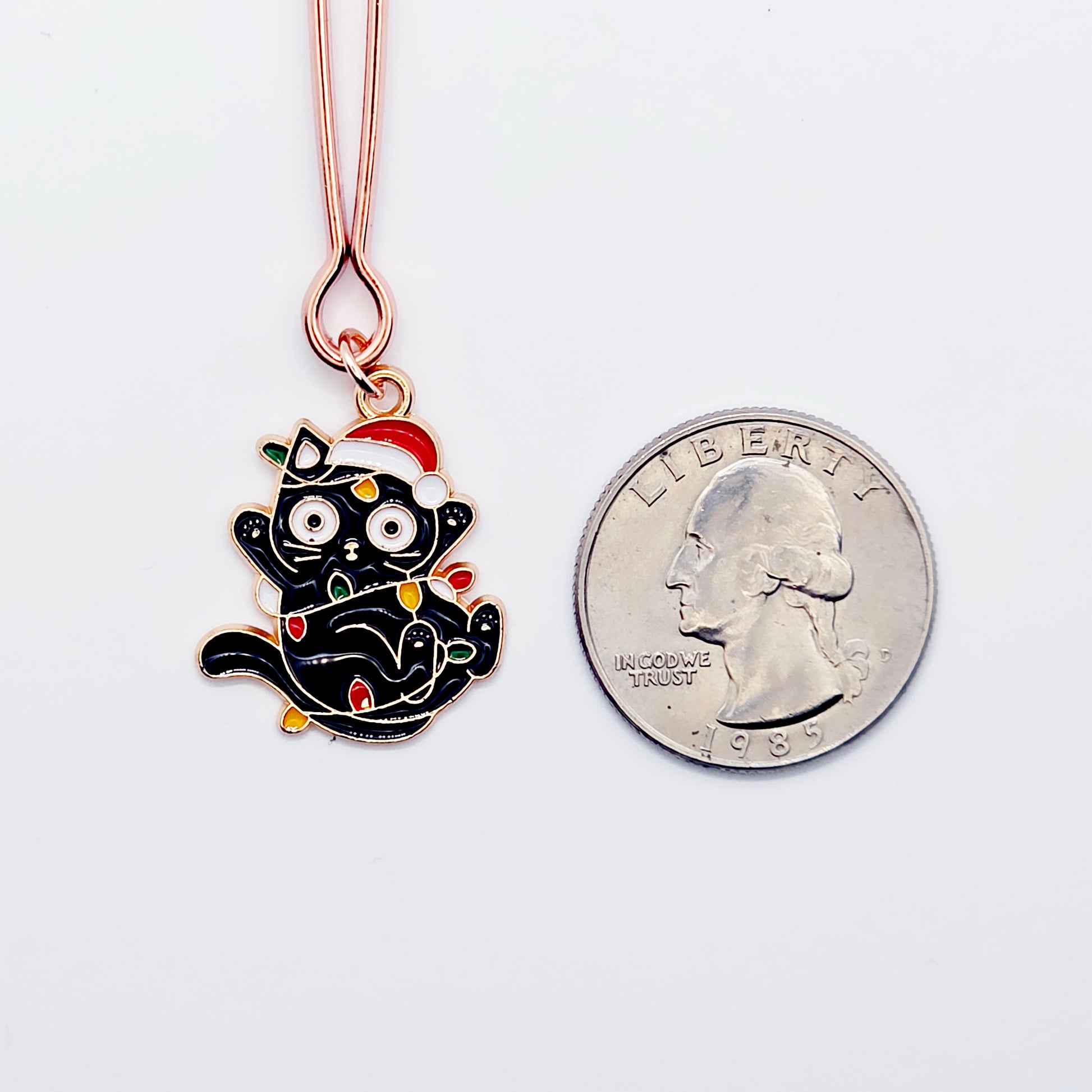  Black Kitten Wrapped in Christmas Lights wearing a Santa Hat next to quarter to show size