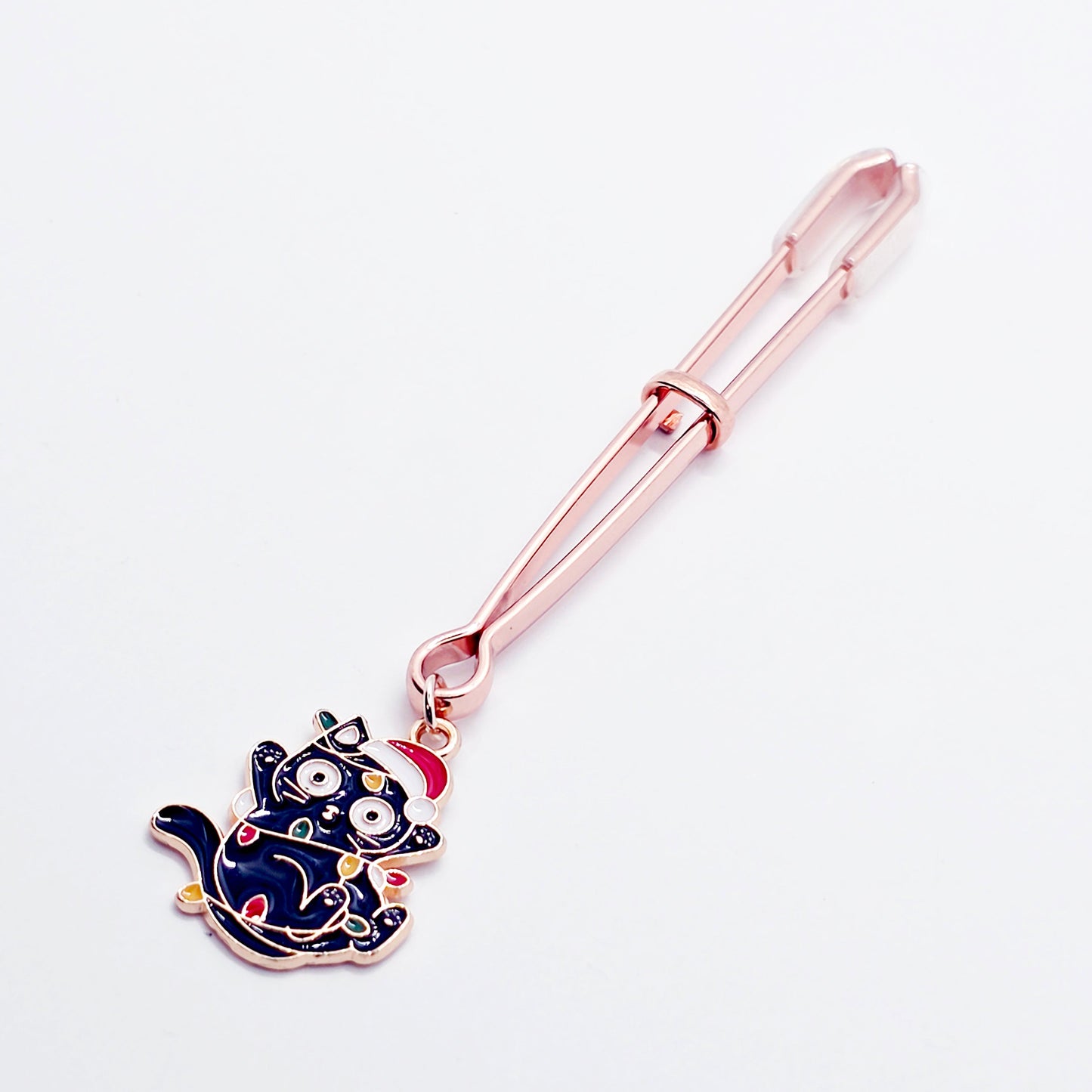 Rose Gold Tweezer Clit Clamp with Black Kitten Wrapped in Christmas Lights wearing a Santa Hat