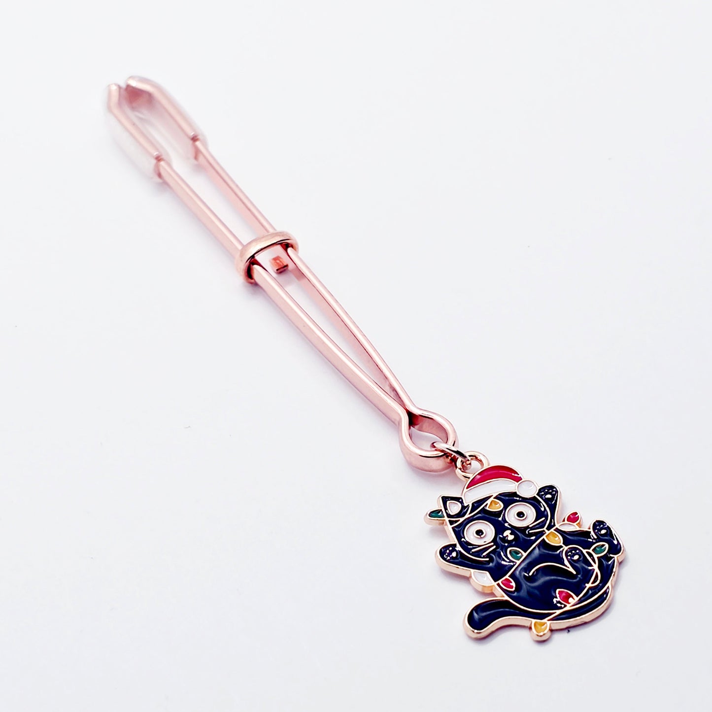 Rose Gold Tweezer Clit Clamp with Black Kitten Wrapped in Christmas Lights wearing a Santa Hat