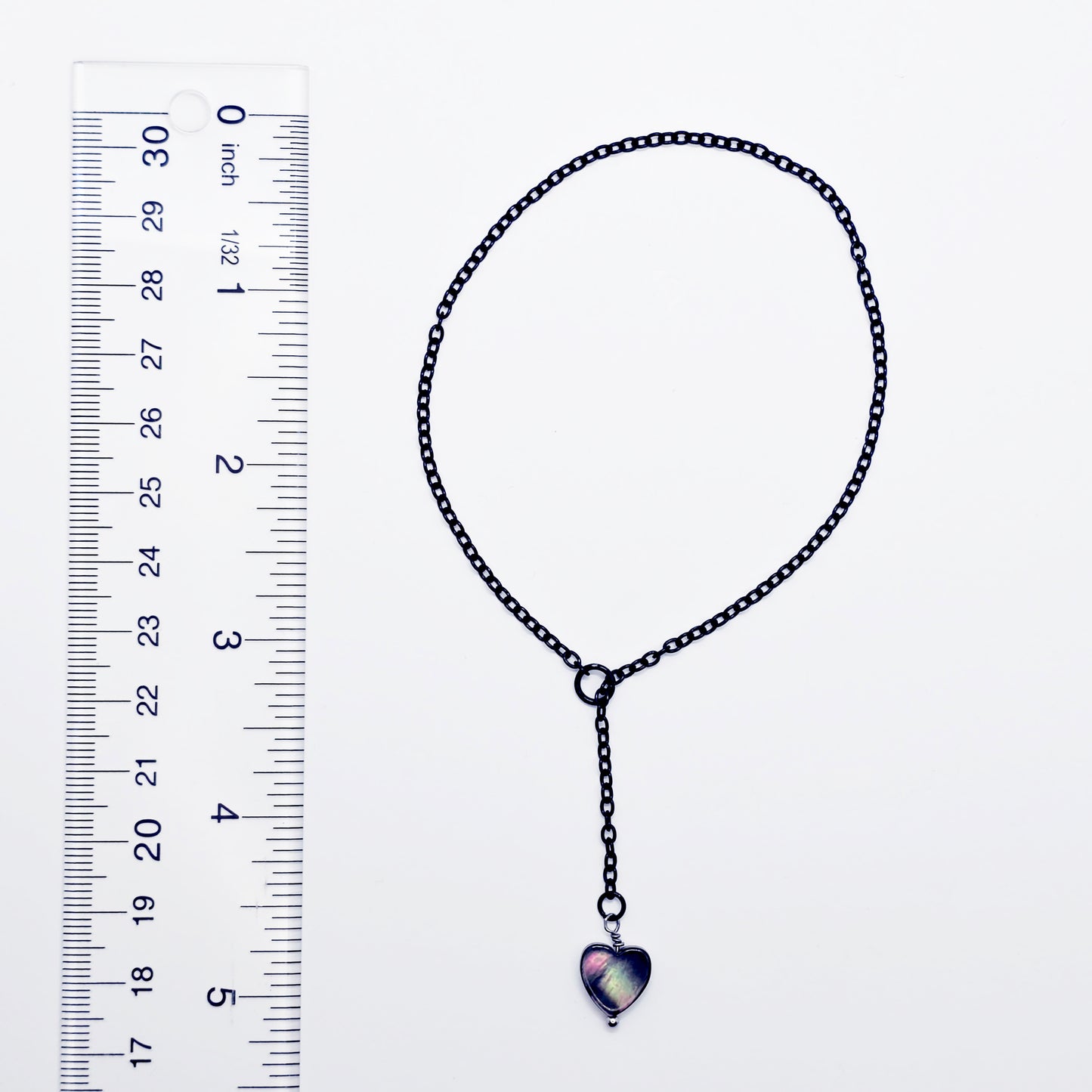This image displays an adjustable penis chain noose paired with a shell-shaped heart, crafted in sleek black and silver colors. The chain is designed to be non-piercing, making it versatile and comfortable for wear.