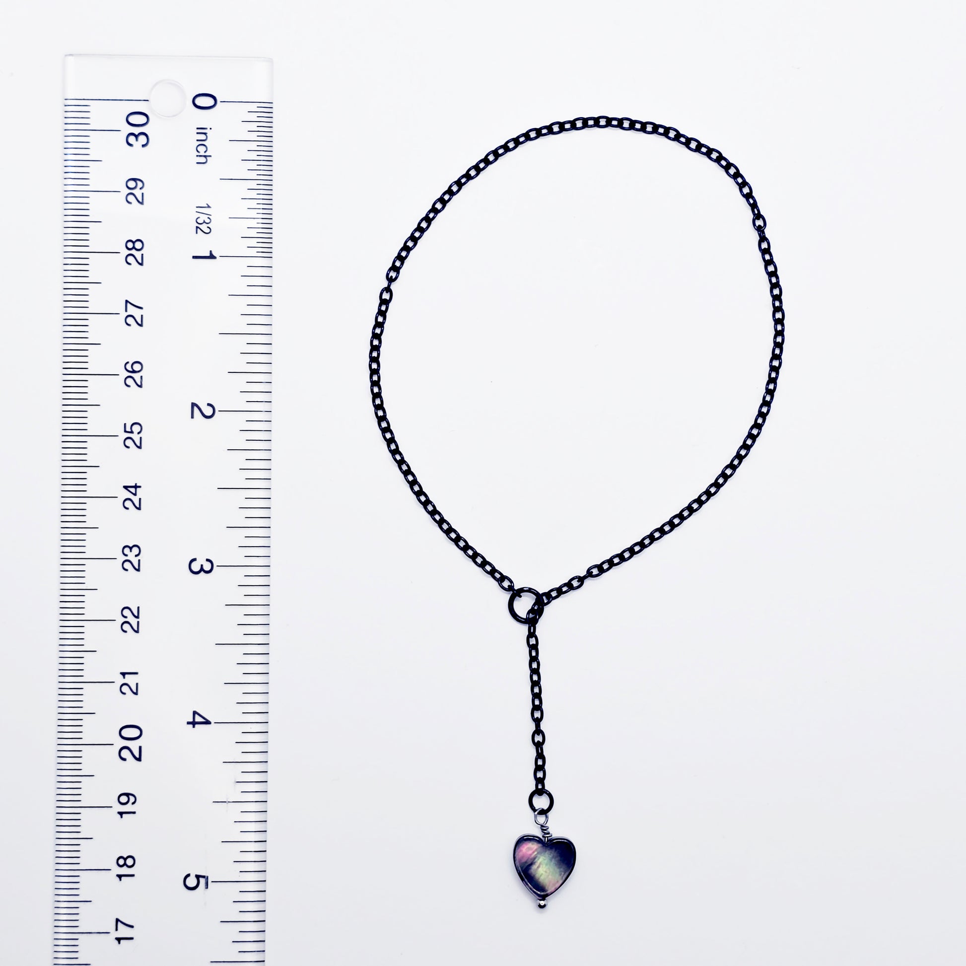 This image displays an adjustable penis chain noose paired with a shell-shaped heart, crafted in sleek black and silver colors. The chain is designed to be non-piercing, making it versatile and comfortable for wear.