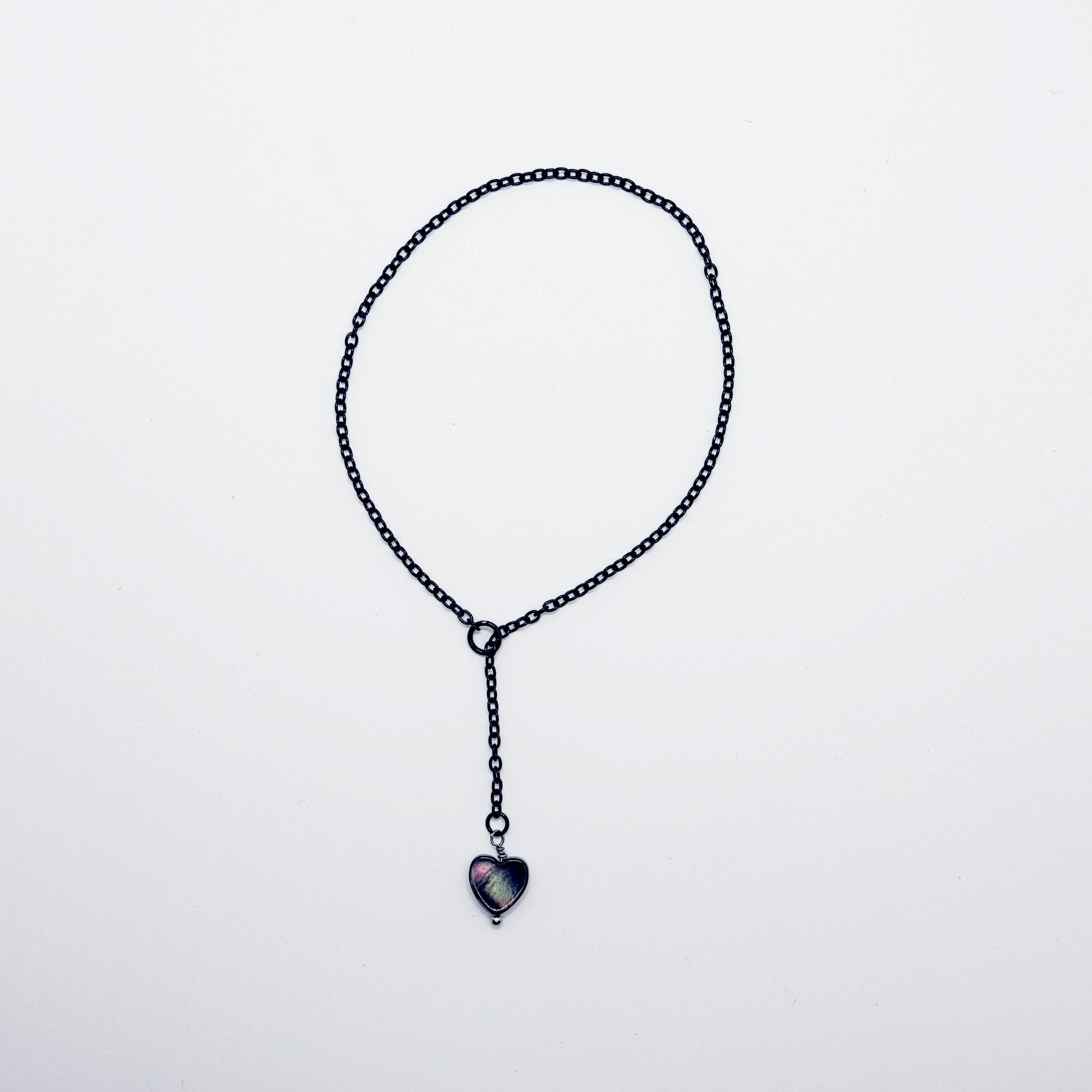 This image displays an adjustable penis chain noose paired with a shell-shaped heart, crafted in sleek black and silver colors. The chain is designed to be non-piercing, making it versatile and comfortable for wear.