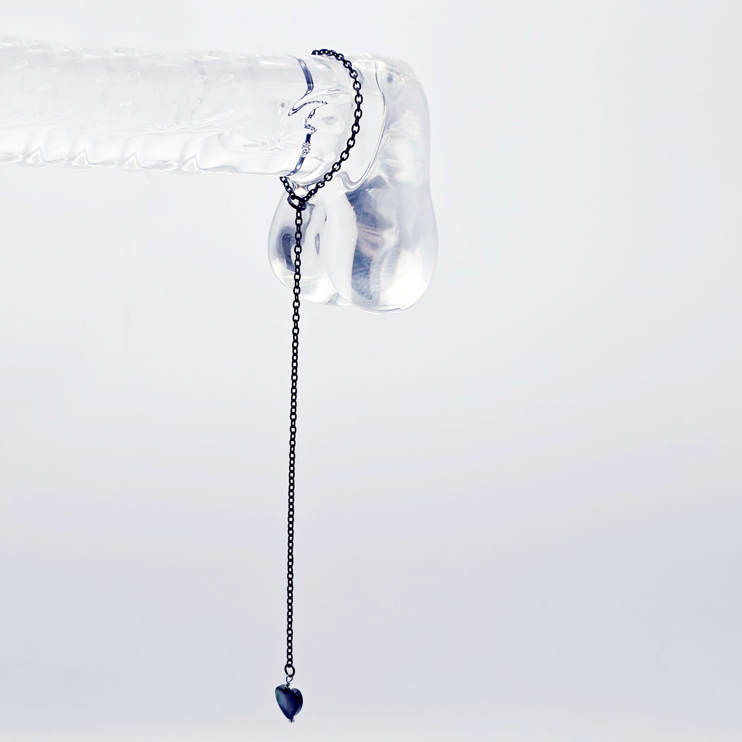 This image displays an adjustable penis chain noose paired with a shell-shaped heart, crafted in sleek black and silver colors. The chain is designed to be non-piercing, making it versatile and comfortable for wear.