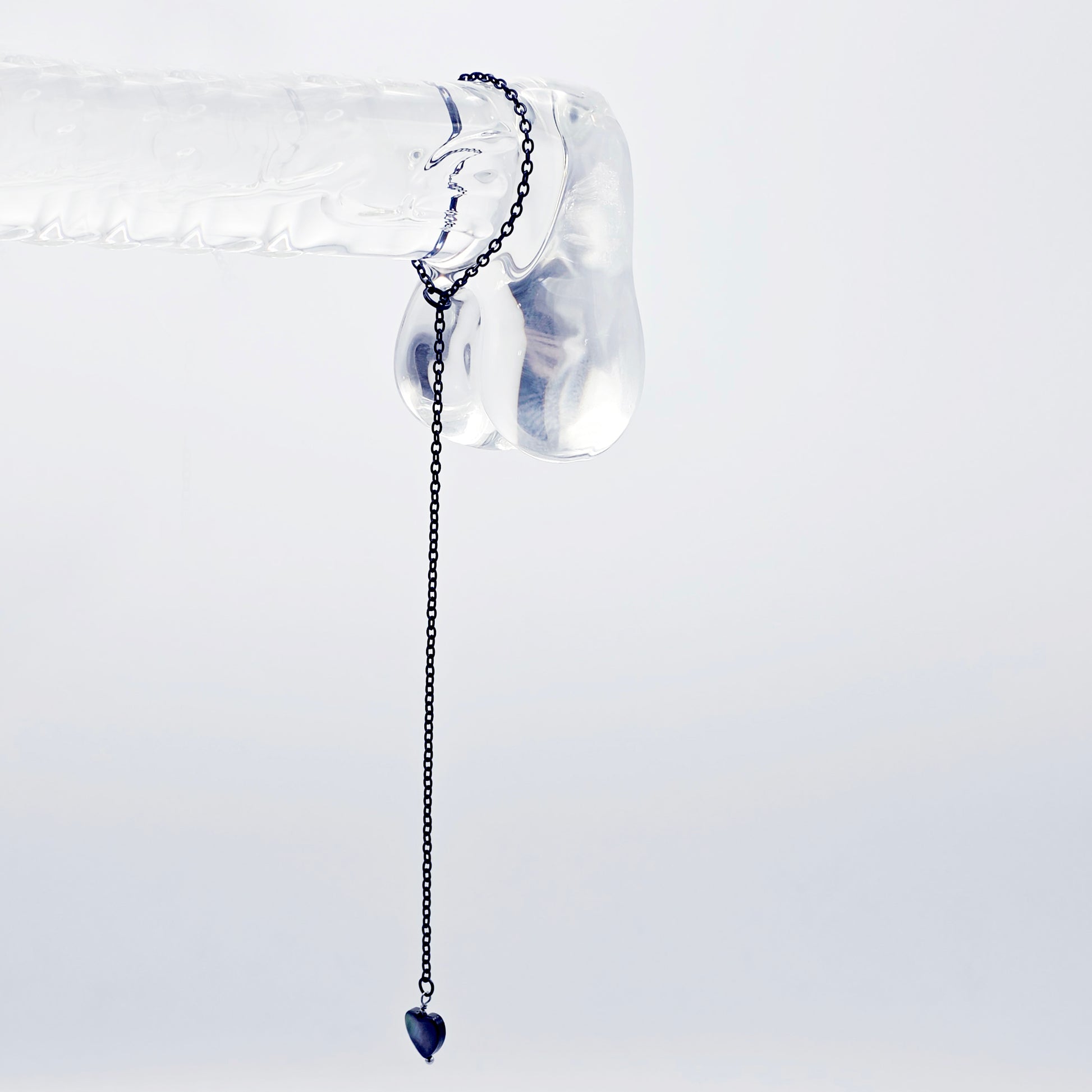 This image displays an adjustable penis chain noose paired with a shell-shaped heart, crafted in sleek black and silver colors. The chain is designed to be non-piercing, making it versatile and comfortable for wear.