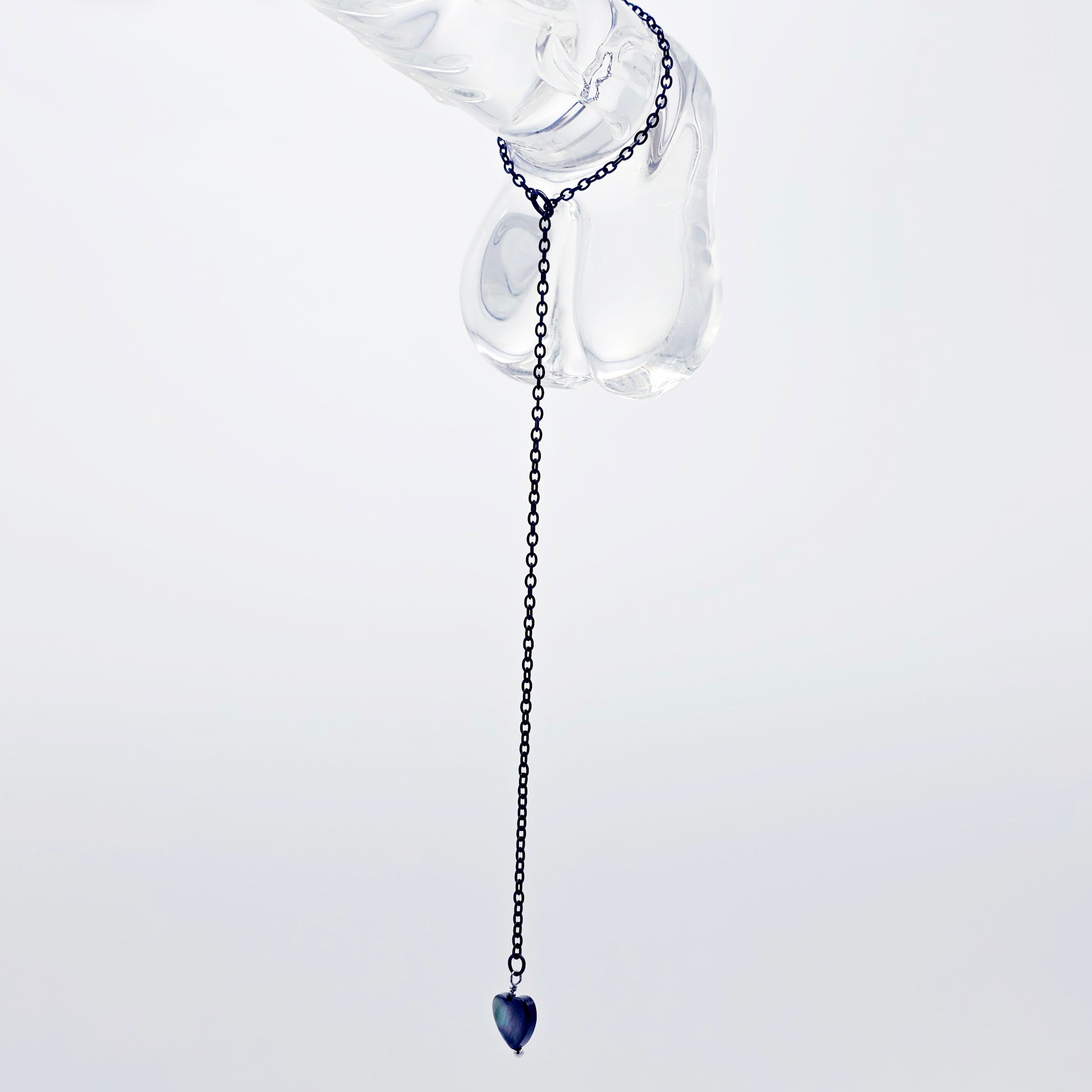 This image displays an adjustable penis chain noose paired with a shell-shaped heart, crafted in sleek black and silver colors. The chain is designed to be non-piercing, making it versatile and comfortable for wear.