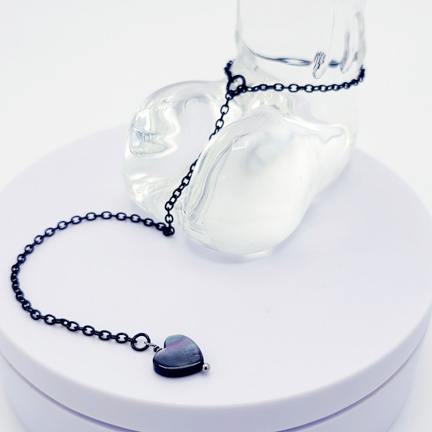 This image displays an adjustable penis chain noose paired with a shell-shaped heart, crafted in sleek black and silver colors. The chain is designed to be non-piercing, making it versatile and comfortable for wear.