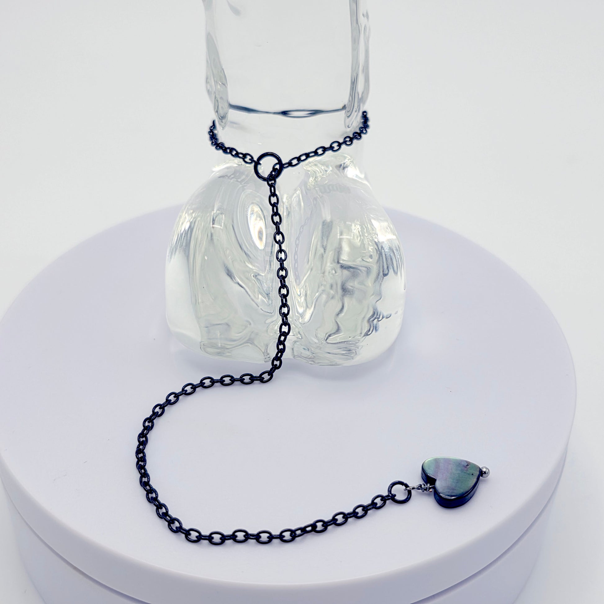 This image displays an adjustable penis chain noose paired with a shell-shaped heart, crafted in sleek black and silver colors. The chain is designed to be non-piercing, making it versatile and comfortable for wear.