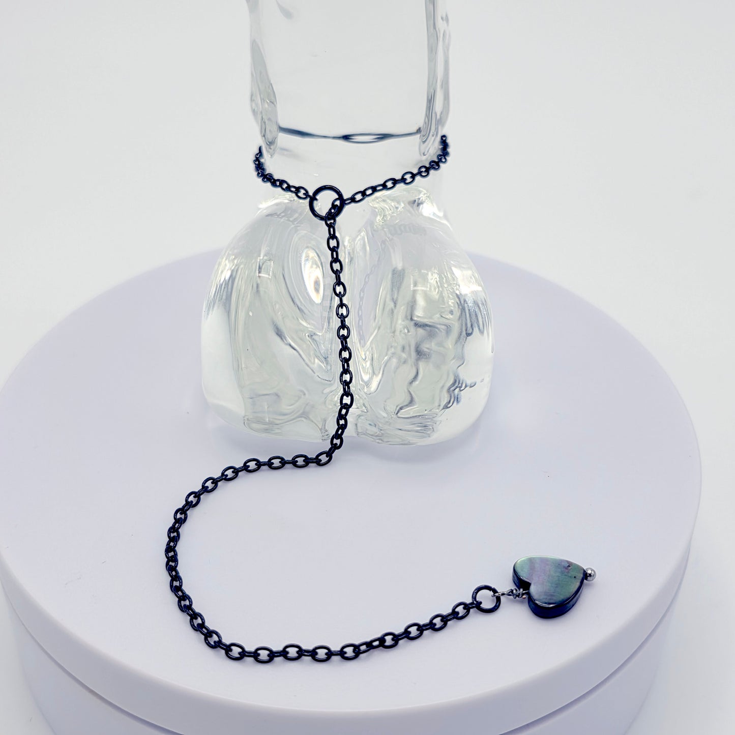 This image displays an adjustable penis chain noose paired with a shell-shaped heart, crafted in sleek black and silver colors. The chain is designed to be non-piercing, making it versatile and comfortable for wear.