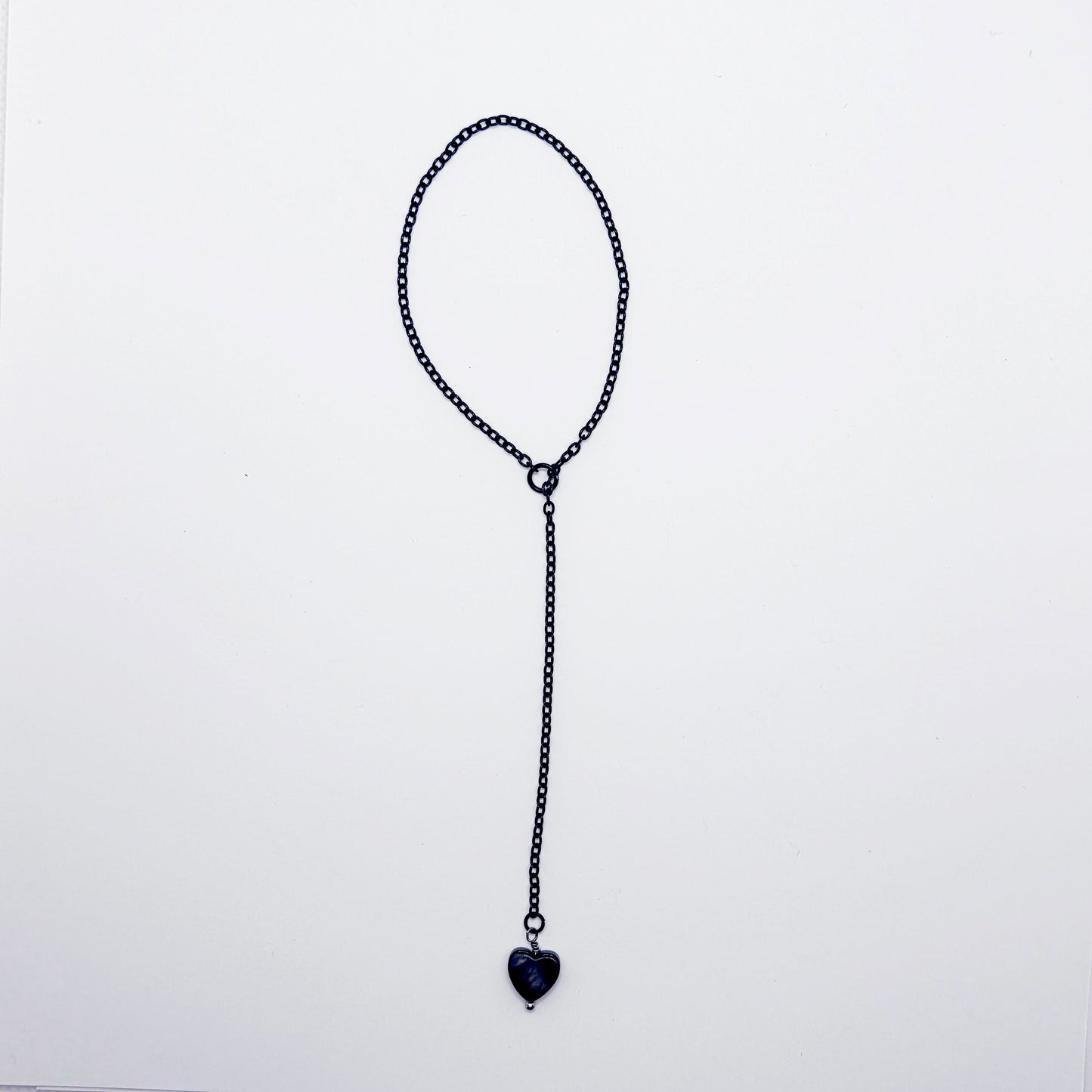 This image displays an adjustable penis chain noose paired with a shell-shaped heart, crafted in sleek black and silver colors. The chain is designed to be non-piercing, making it versatile and comfortable for wear.