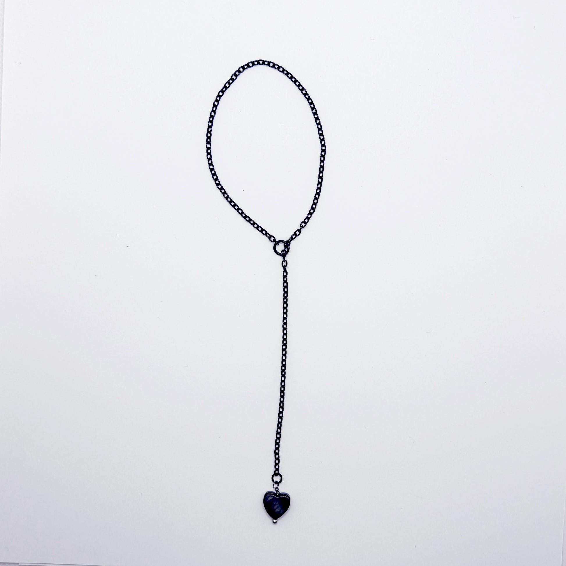 This image displays an adjustable penis chain noose paired with a shell-shaped heart, crafted in sleek black and silver colors. The chain is designed to be non-piercing, making it versatile and comfortable for wear.