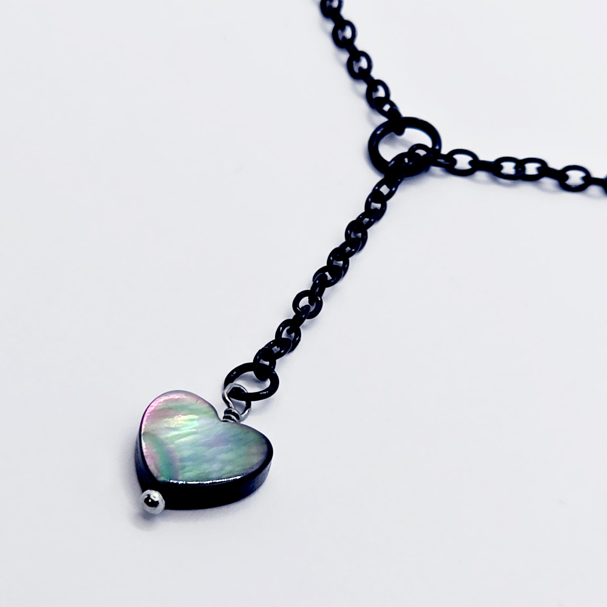 This image displays an adjustable penis chain noose paired with a shell-shaped heart, crafted in sleek black and silver colors. The chain is designed to be non-piercing, making it versatile and comfortable for wear.