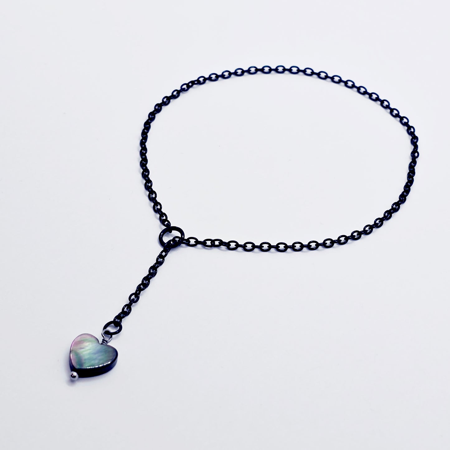 This image displays an adjustable penis chain noose paired with a shell-shaped heart, crafted in sleek black and silver colors. The chain is designed to be non-piercing, making it versatile and comfortable for wear.