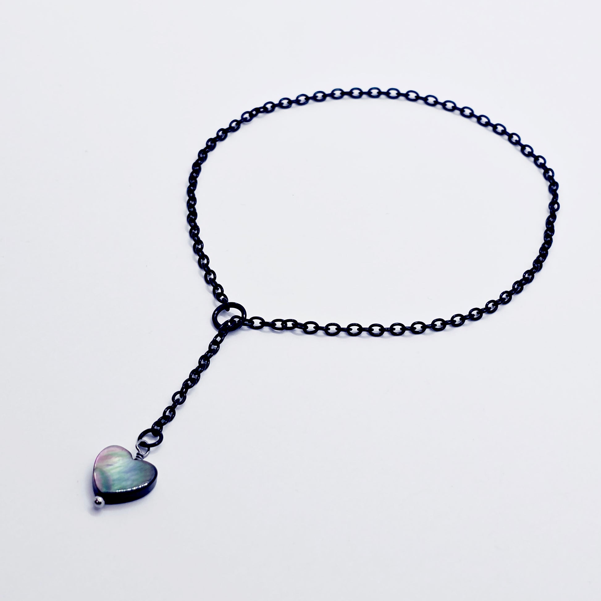 This image displays an adjustable penis chain noose paired with a shell-shaped heart, crafted in sleek black and silver colors. The chain is designed to be non-piercing, making it versatile and comfortable for wear.