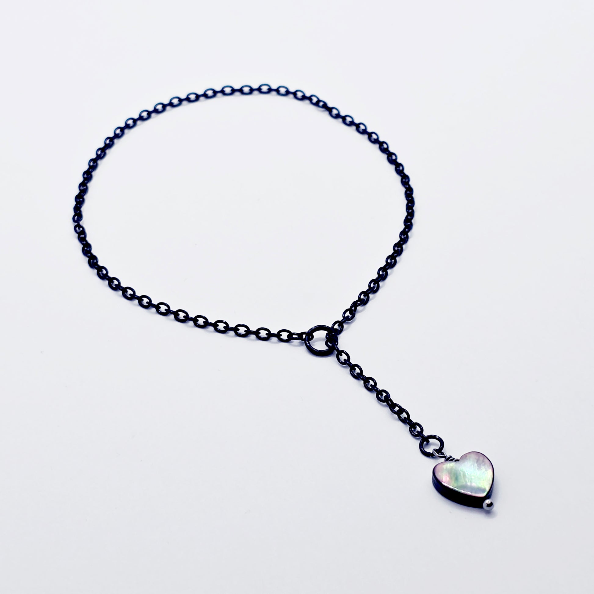 This image displays an adjustable penis chain noose paired with a shell-shaped heart, crafted in sleek black and silver colors. The chain is designed to be non-piercing, making it versatile and comfortable for wear.