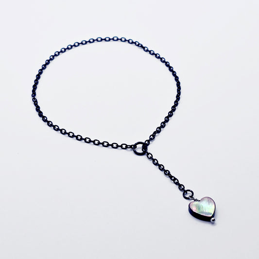 This image displays an adjustable penis chain noose paired with a shell-shaped heart, crafted in sleek black and silver colors. The chain is designed to be non-piercing, making it versatile and comfortable for wear.