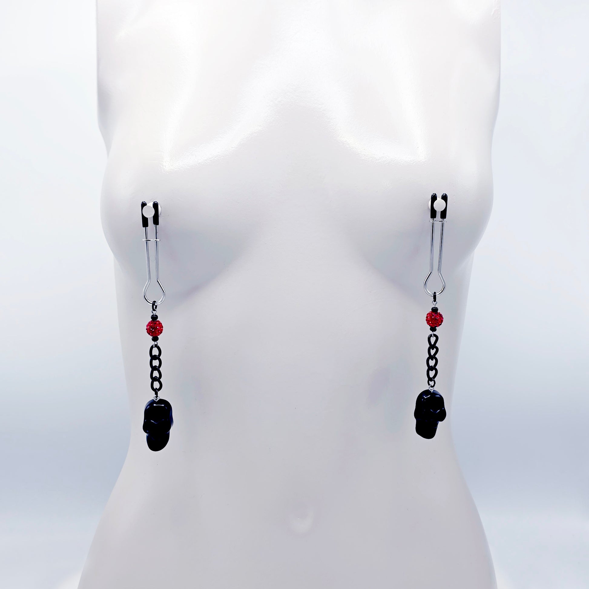 Pair of black skull Nipple Clamps with red beads on a white background