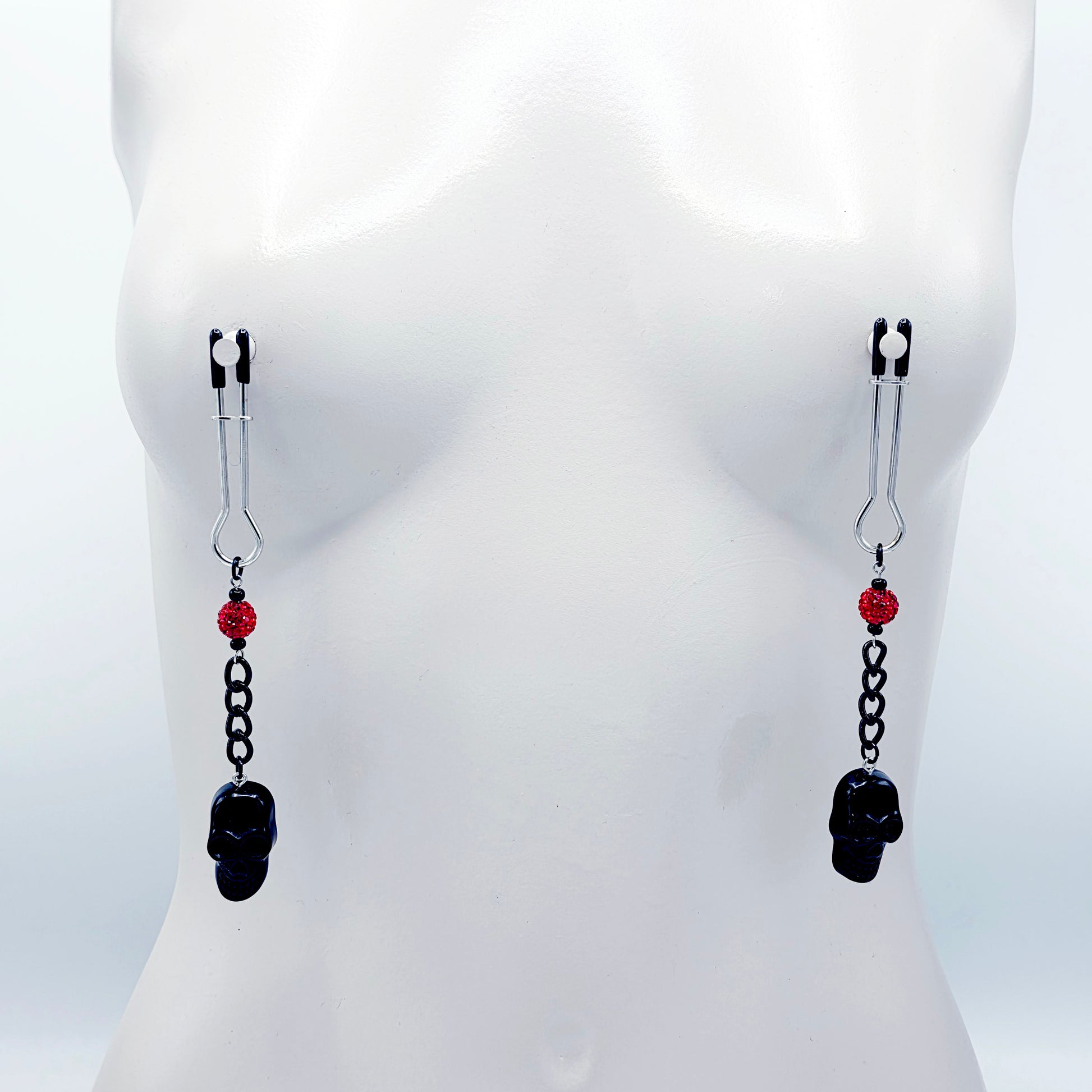 Pair of black skull Nipple Clamps with red beads on a white background