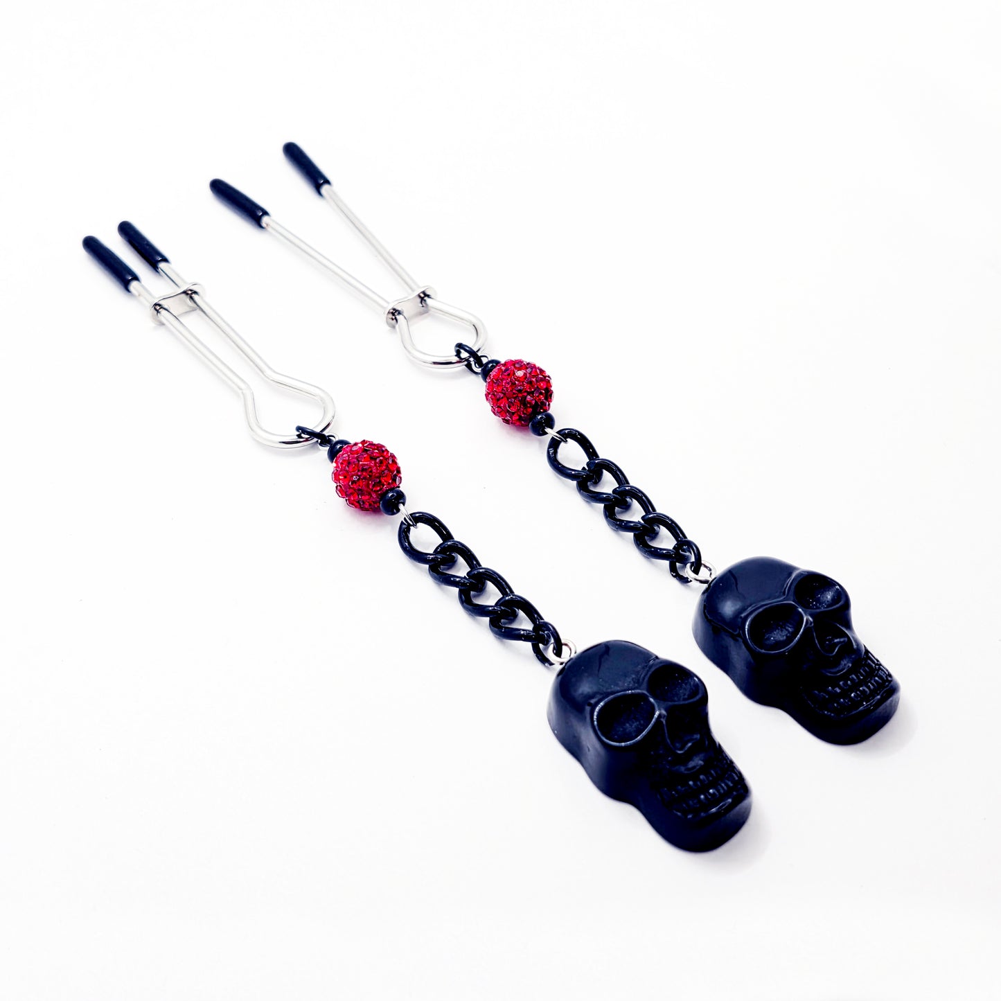 Pair of black skull Nipple Clamps with red beads on a white background