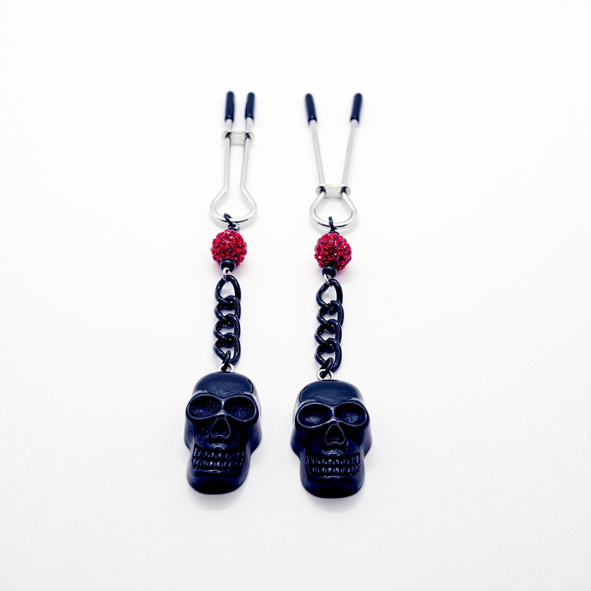 Pair of black skull Nipple Clamps with red beads on a white background