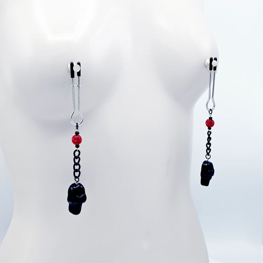 Pair of black skull Nipple Clamps with red beads on a white background
