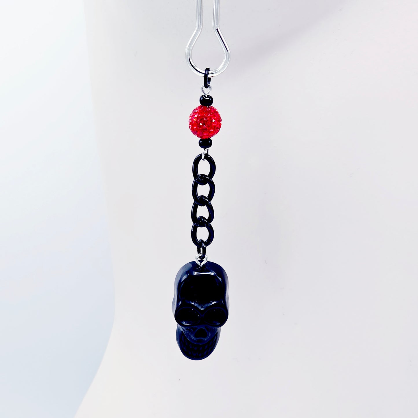 Pair of black skull Nipple Clamps with red beads on a white background