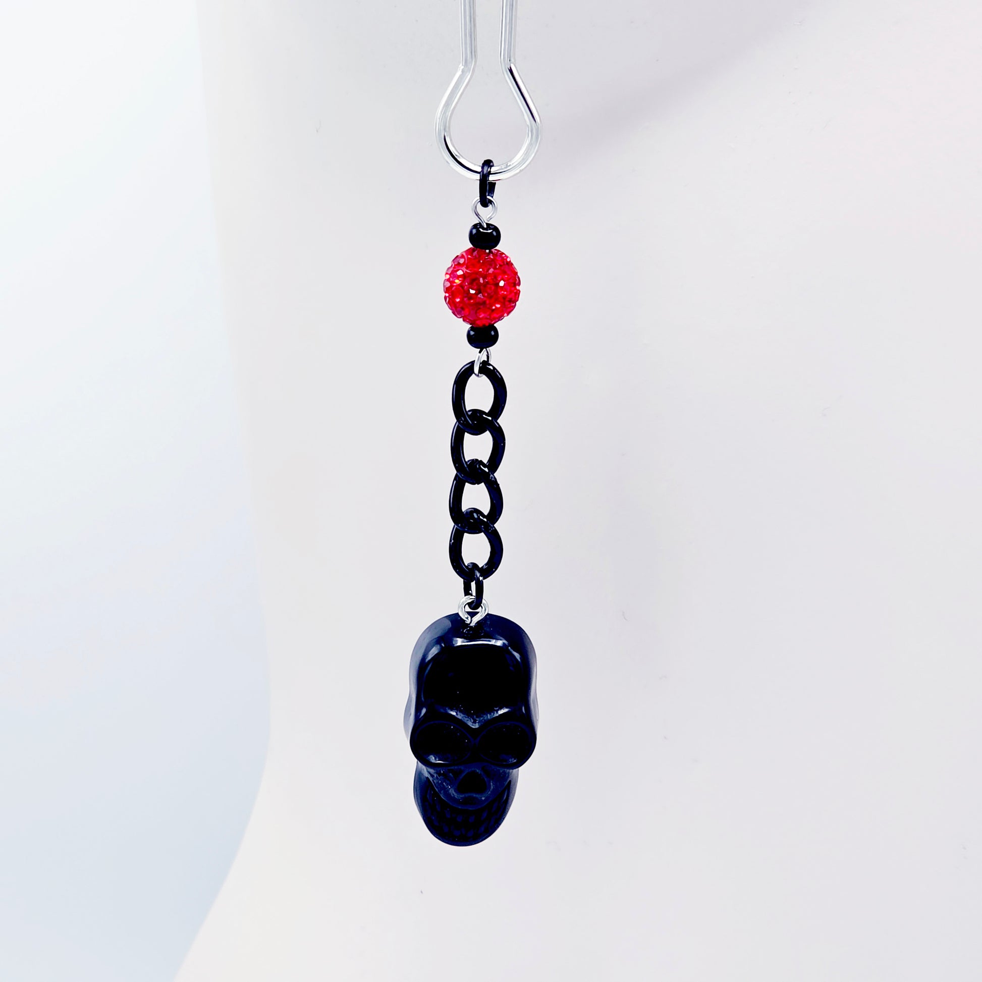 Pair of black skull Nipple Clamps with red beads on a white background