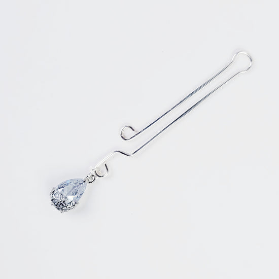 A non-piercing labia clip with a cubic zirconia pendant. The clip and pendant are silver-colored and designed for intimate use.