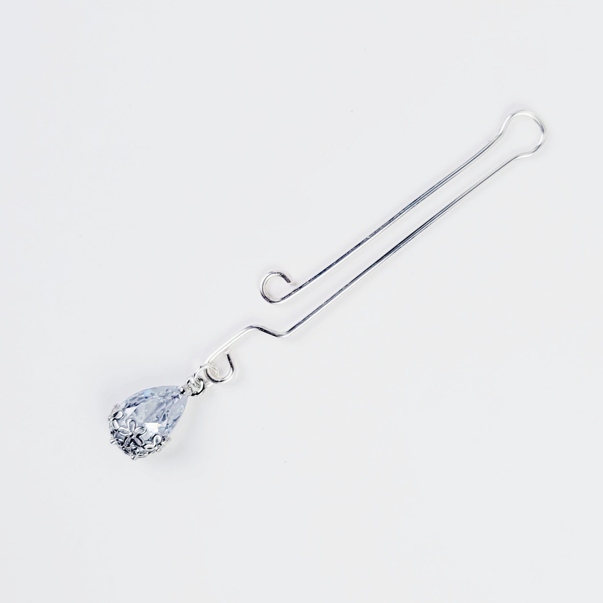 A non-piercing labia clip with a cubic zirconia pendant. The clip and pendant are silver-colored and designed for intimate use.