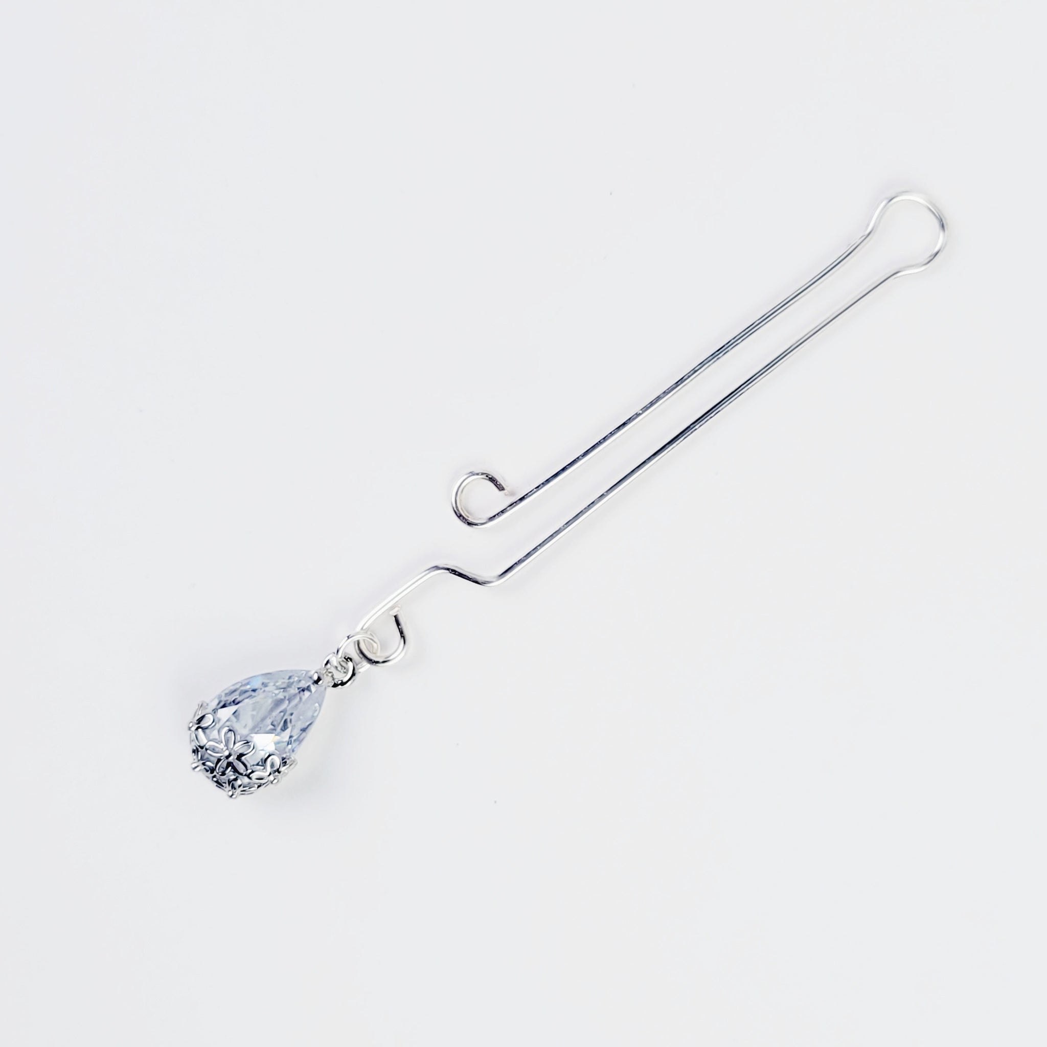 A non-piercing labia clip with a cubic zirconia pendant. The clip and pendant are silver-colored and designed for intimate use.