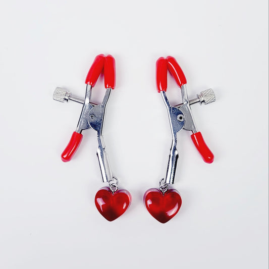 A pair of red adjustable nipple clamps with heart accents.
