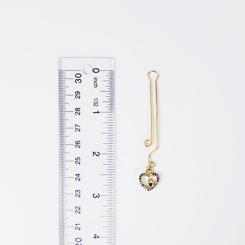 Gold Labia Clip with Gemstone Heart Next to Ruler  